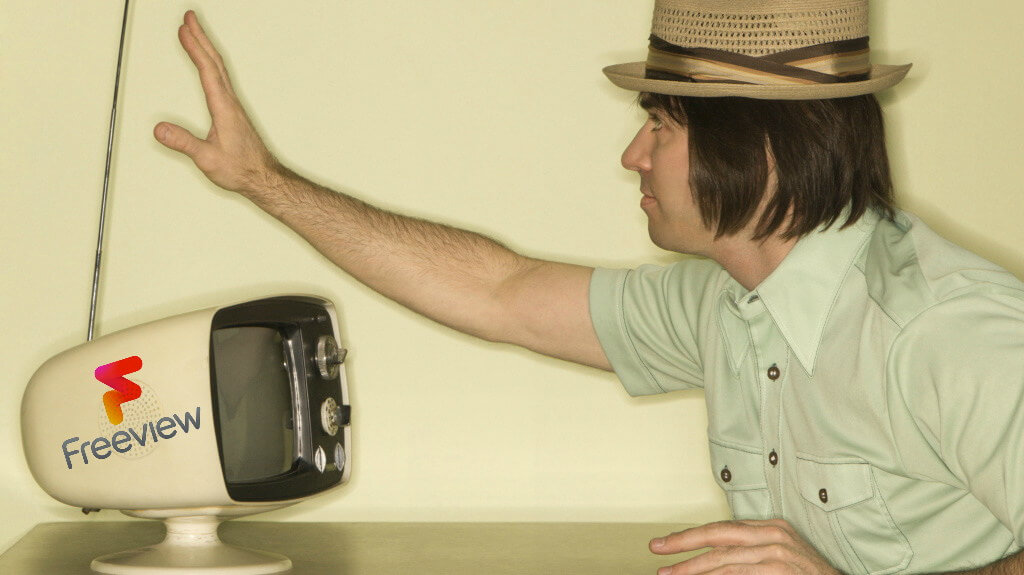 Man tuning an aerial on an old TV to get Freeview