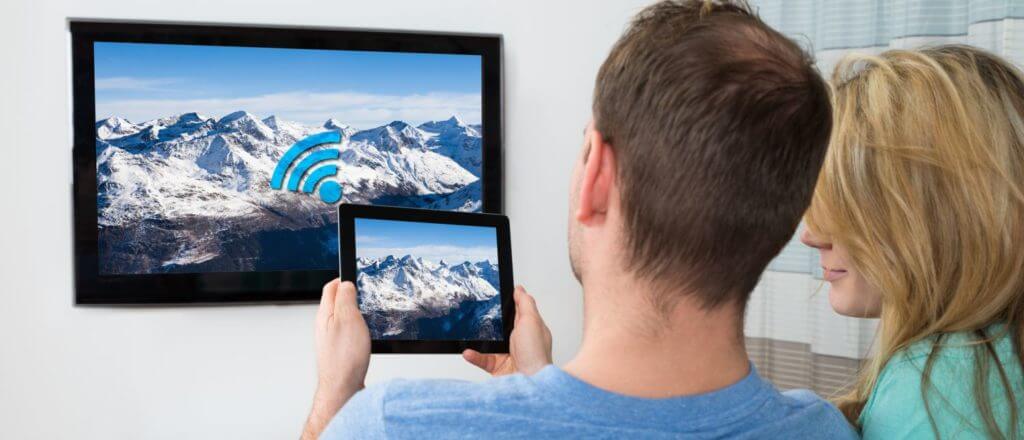 Cord cutters man and woman holding a tablet in front of a TV