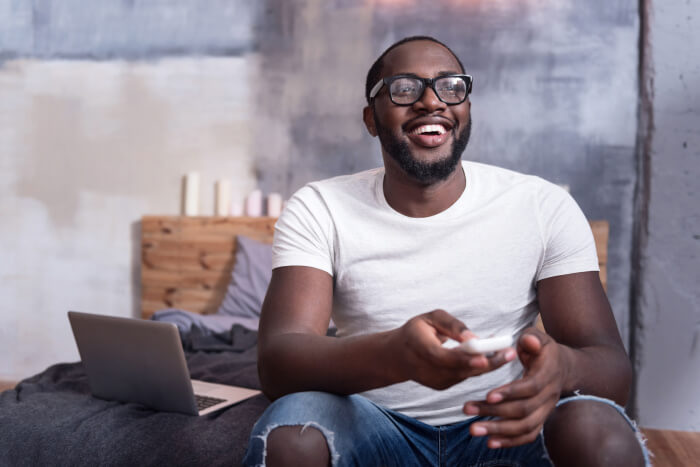 Man holding tv remote in bed700