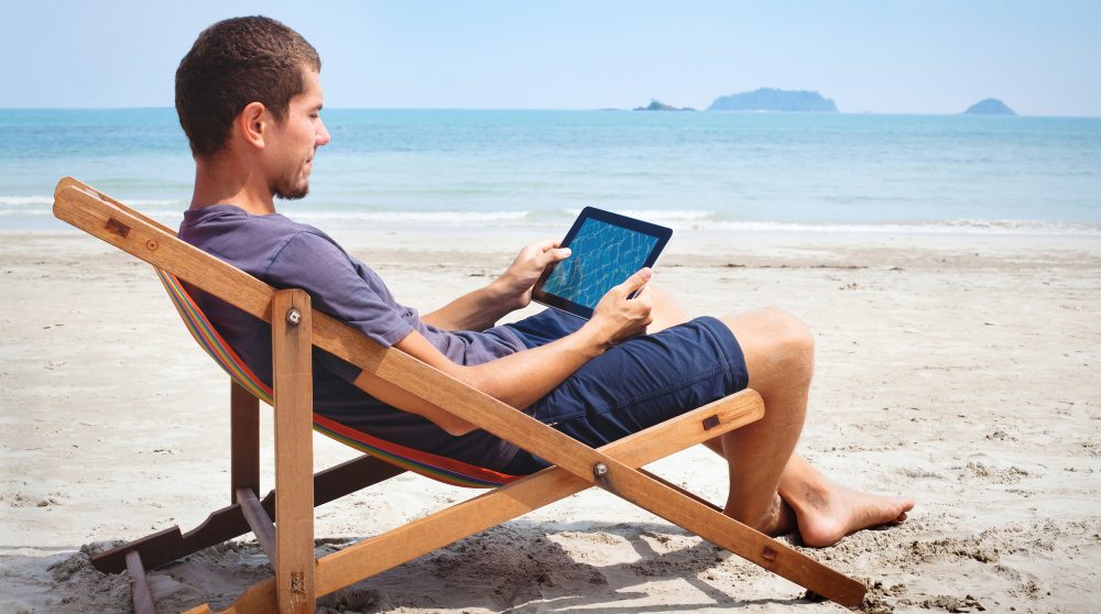 Man watching a tablet on the beach vacation