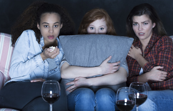 Three women watching scary TV horror film