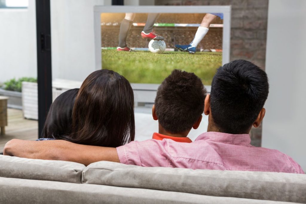 family watching football on tv sofa