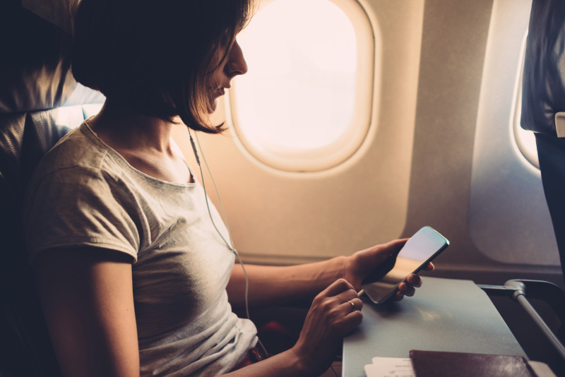 woman watching her smartphone on a plane 800