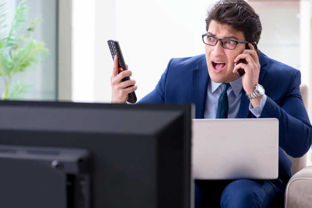 Angry man watching TV with phone